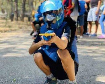 Enfant accroupi durant une partie de paintball avec un lanceur Gotcha